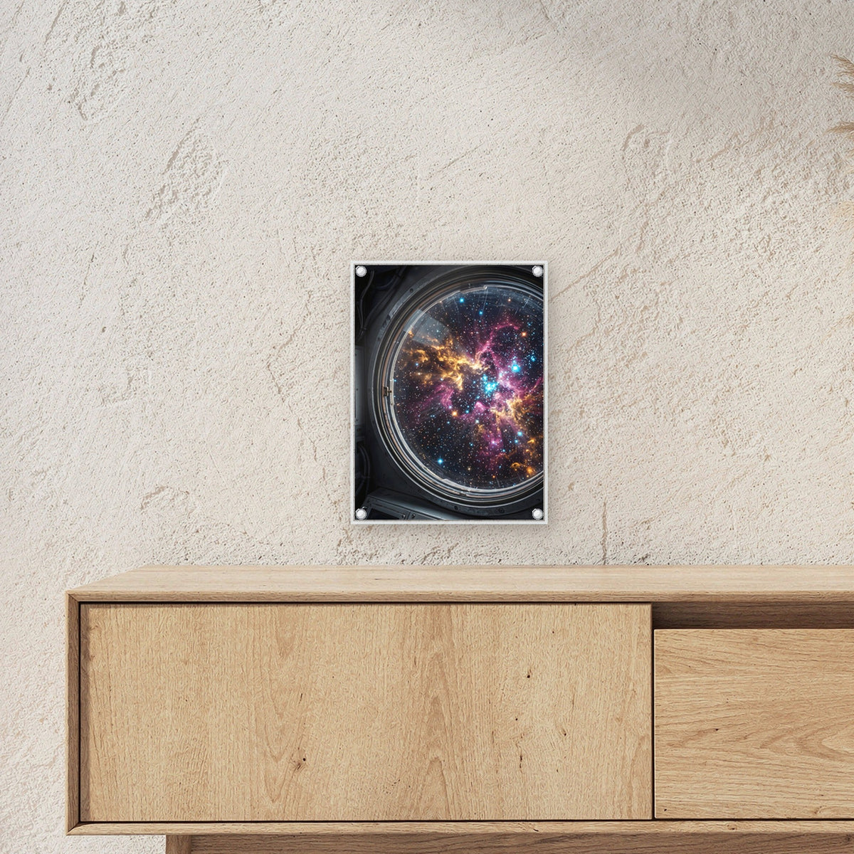 Blick durchs Bullauge – Rundes Bullauge mit Sternennebel in Pink und Gold, auf Acrylglas mit Abstandshaltern, über einem Sideboard