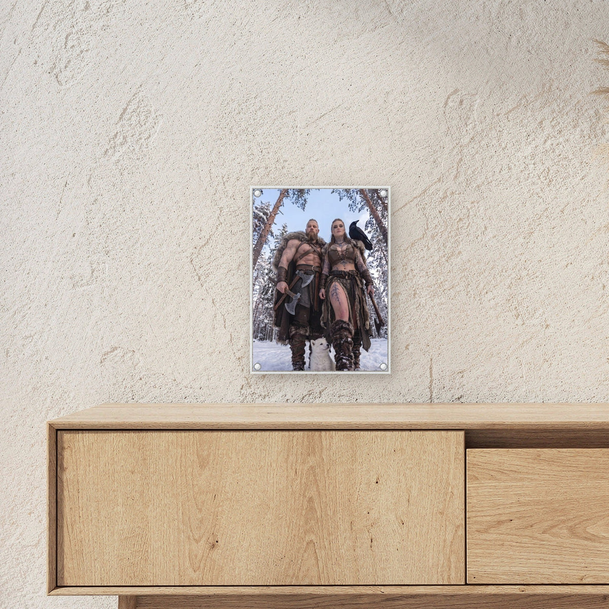 Der erste Winter – Wikingerpaar mit weißem Welpen im verschneiten Wald, auf Acrylglas mit Abstandshaltern, über einem Sideboard
