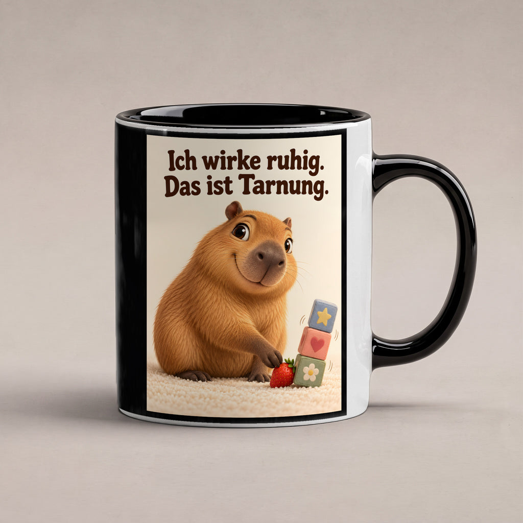 Ruhe mit Plan – Capybara-Tasse mit Spruch. Spruch: Ich wirke ruhig. Das ist Tarnung. Beidseitiges Hochformatmotiv. 1 STUDIO. Innen schwarz.