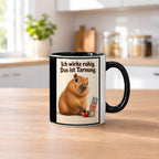 Ruhe mit Plan – Capybara-Tasse mit Spruch. Spruch: Ich wirke ruhig. Das ist Tarnung. Beidseitiges Hochformatmotiv. 2 KUECHE. Innen schwarz.