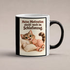 Schlafanzugglück – Katzentasse mit Spruch. Spruch: Meine Motivation steckt noch im Schlafanzug. Beidseitige Motivansicht. 1 STUDIO HEISS. Zaubertasse: Wärmeeffekt.
