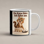Samtpfotenleitung – Katzentasse mit Spruch. Spruch: Die Katze führt. Ich führe aus. Beidseitige Motivansicht. 1 STUDIO. Weiß.