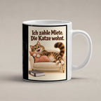Wohnrecht mit Fell – Katzentasse mit Spruch. Spruch: Ich zahle Miete. Die Katze wohnt. Beidseitige Motivansicht. 1 STUDIO. Weiß.