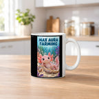Ein rosa Axolotl ruht in einer schimmernden Muschel mit einer Blase auf dem Kopf; daneben sitzt eine Schnecke. Spruch: MAX AURA FARMING – weiße Tasse, Küchenansicht.