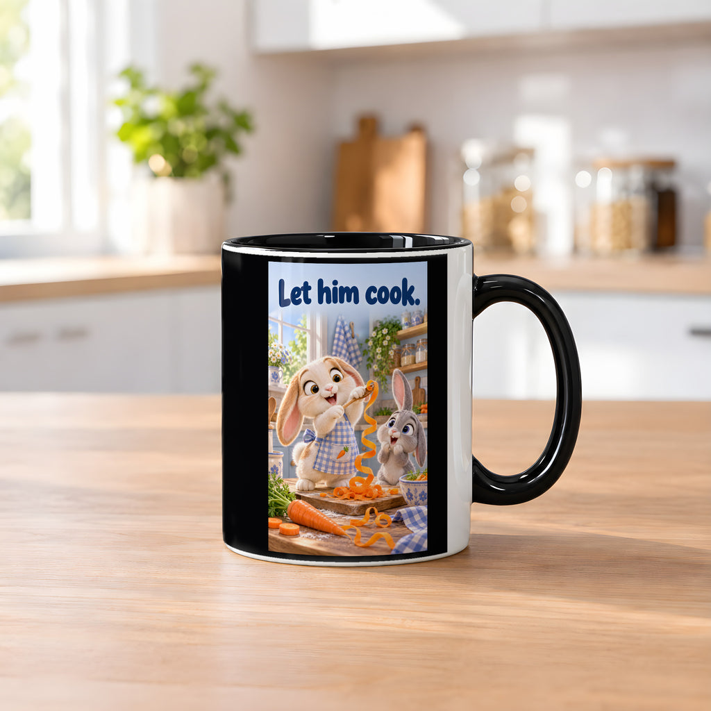 Zwei Kaninchen spielen in einer hellen Küche mit langen Möhrenstreifen; eines trägt eine karierte Schürze. Spruch: Let him cook. – Tasse innen schwarz, Küchenansicht.