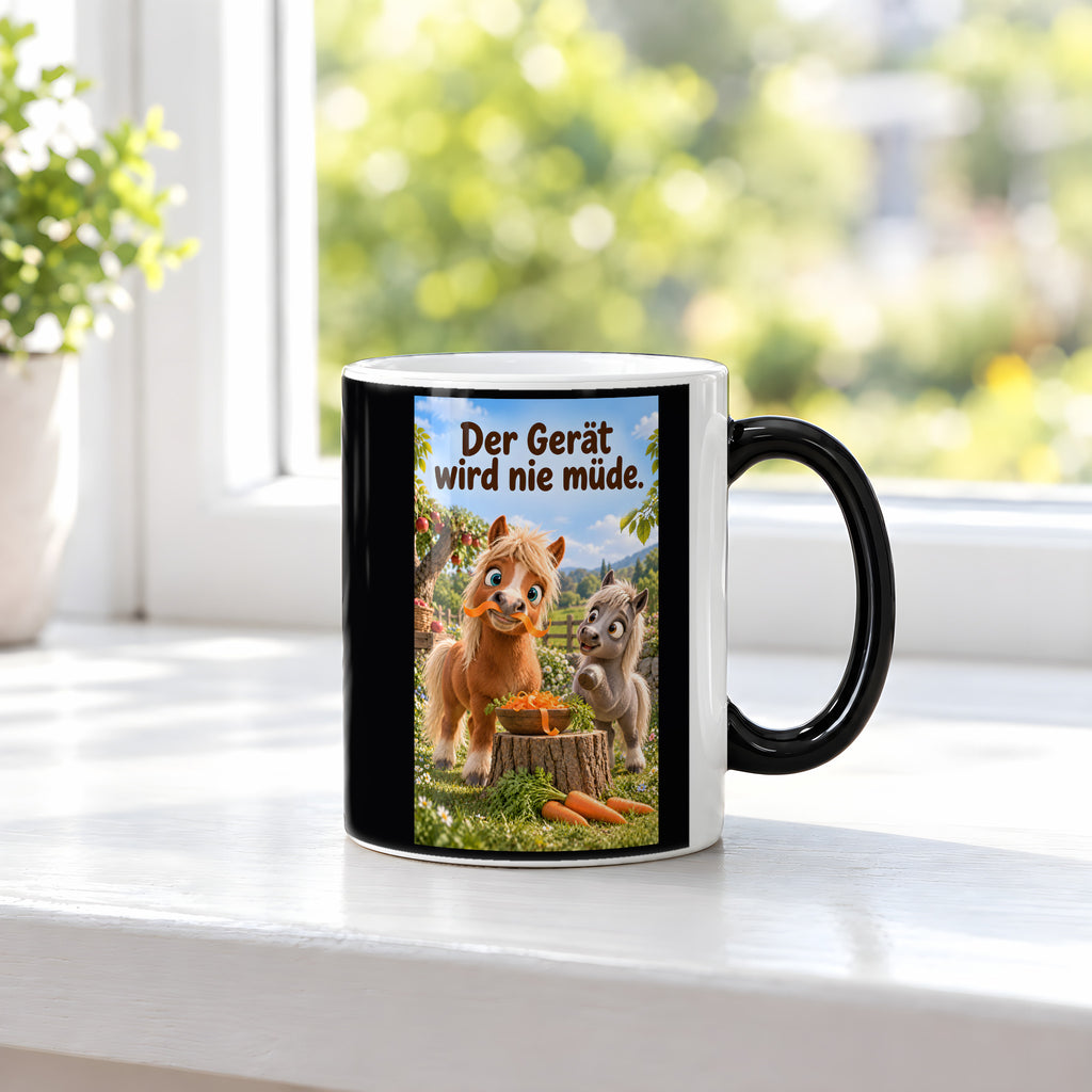 Ein braunes Pony trägt einen Möhrenstreifen als Schnurrbart; daneben lacht ein graues Pony vor einer Schale Möhrenstreifen. Spruch: Der Gerät wird nie müde. – Black Edition mit Wärmeeffekt, Ansicht am Fenster.