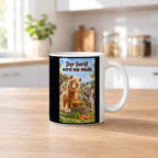 Ein braunes Pony trägt einen Möhrenstreifen als Schnurrbart; daneben lacht ein graues Pony vor einer Schale Möhrenstreifen. Spruch: Der Gerät wird nie müde. – weiße Tasse, Küchenansicht.