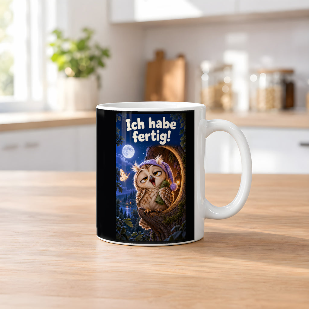 Eine müde Eule mit violetter Schlafmütze gähnt vor einer Baumhöhle unter dem Mond und hält ein kleines Blätterbündel. Spruch: Ich habe fertig! – weiße Tasse, Küchenansicht.