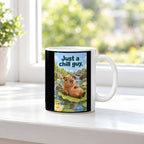 Ein entspanntes Capybara mit einem Blatt auf dem Kopf liegt auf einem großen Seerosenblatt; eine kleine Schildkröte schwimmt daneben. Spruch: Just a chill guy. – weiße Tasse, Ansicht am Fenster.