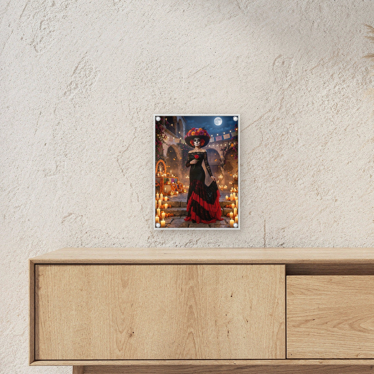 Die Catrina – Frau mit Totenkopf-Schminke und Blumenhut im Hof voller Kerzen und Ringelblumen, auf Acrylglas mit Edelstahl-Abstandshaltern, über einem Sideboard, zeigt die Größe im Raum