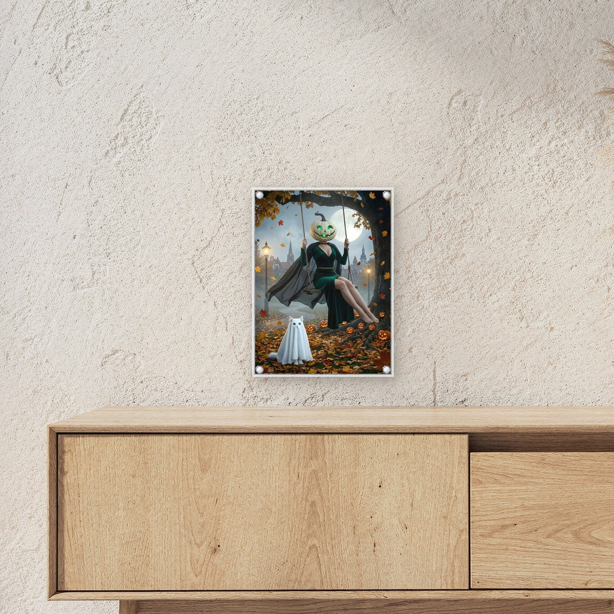 Die Herbstschaukel – Frau mit grünem Kürbiskopf auf der Schaukel unter dem Baum mit Katzengespenst, auf Acrylglas mit Edelstahl-Abstandshaltern, über einem Sideboard, zeigt die Größe im Raum