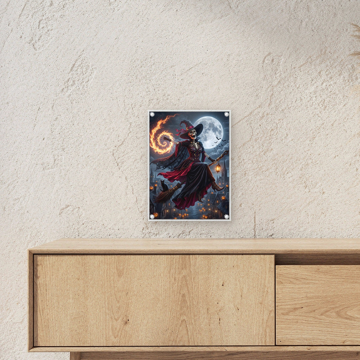 Die Besenkönigin – Skelett-Hexe fliegt auf dem Besen mit Feuerspirale über die Stadt, auf Acrylglas mit Edelstahl-Abstandshaltern, über einem Sideboard, zeigt die Größe im Raum
