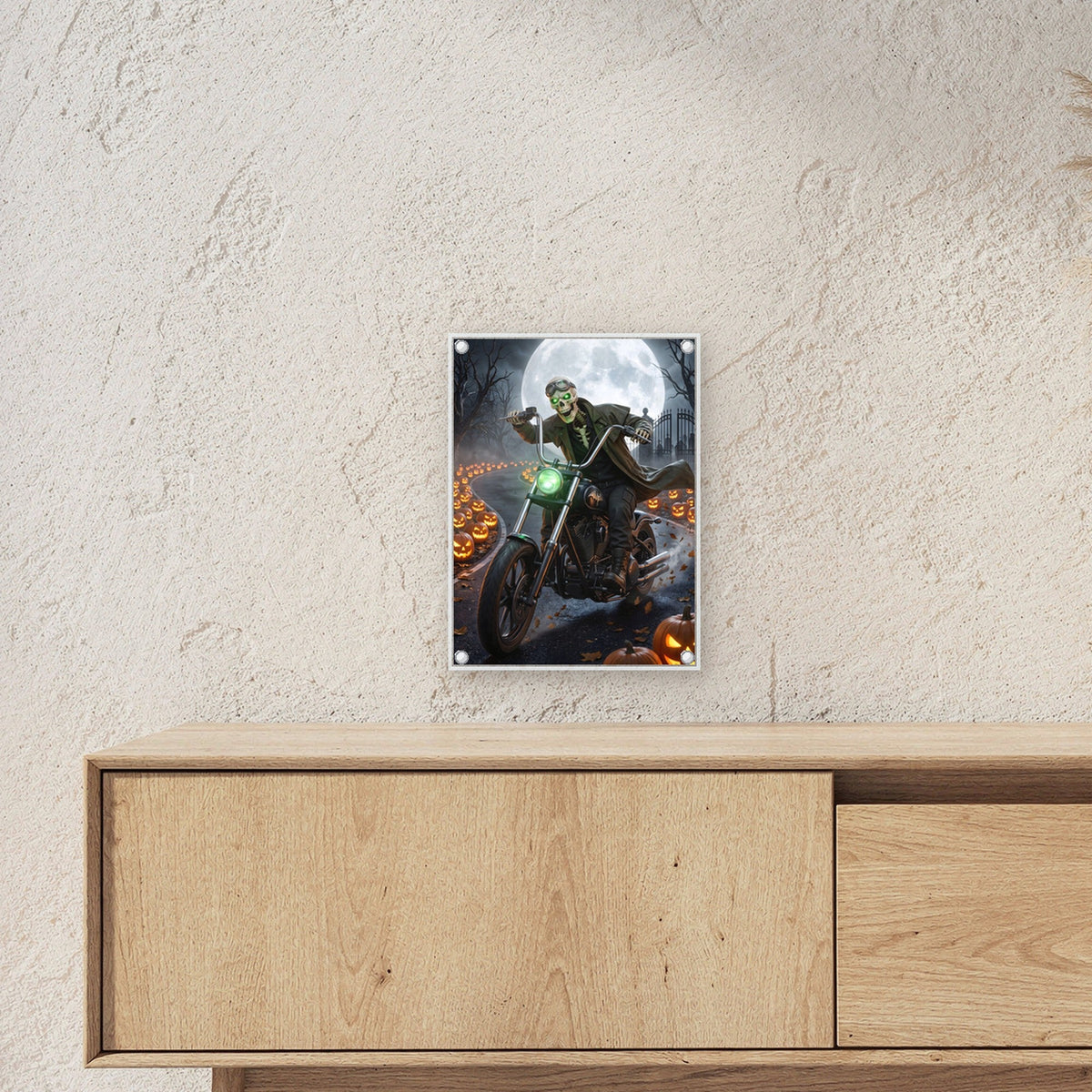 Der Knochenbiker – Skelett mit Fliegerbrille rast auf dem Motorrad durch die Kürbisallee, auf Acrylglas mit Edelstahl-Abstandshaltern, über einem Sideboard, zeigt die Größe im Raum