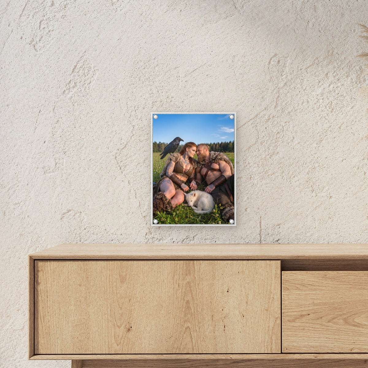Mittsommer – Wikingerpaar mit Rabe und schlafendem Welpen auf der Sommerwiese, auf Acrylglas mit Edelstahl-Abstandshaltern, über einem Sideboard, zeigt die Größe im Raum