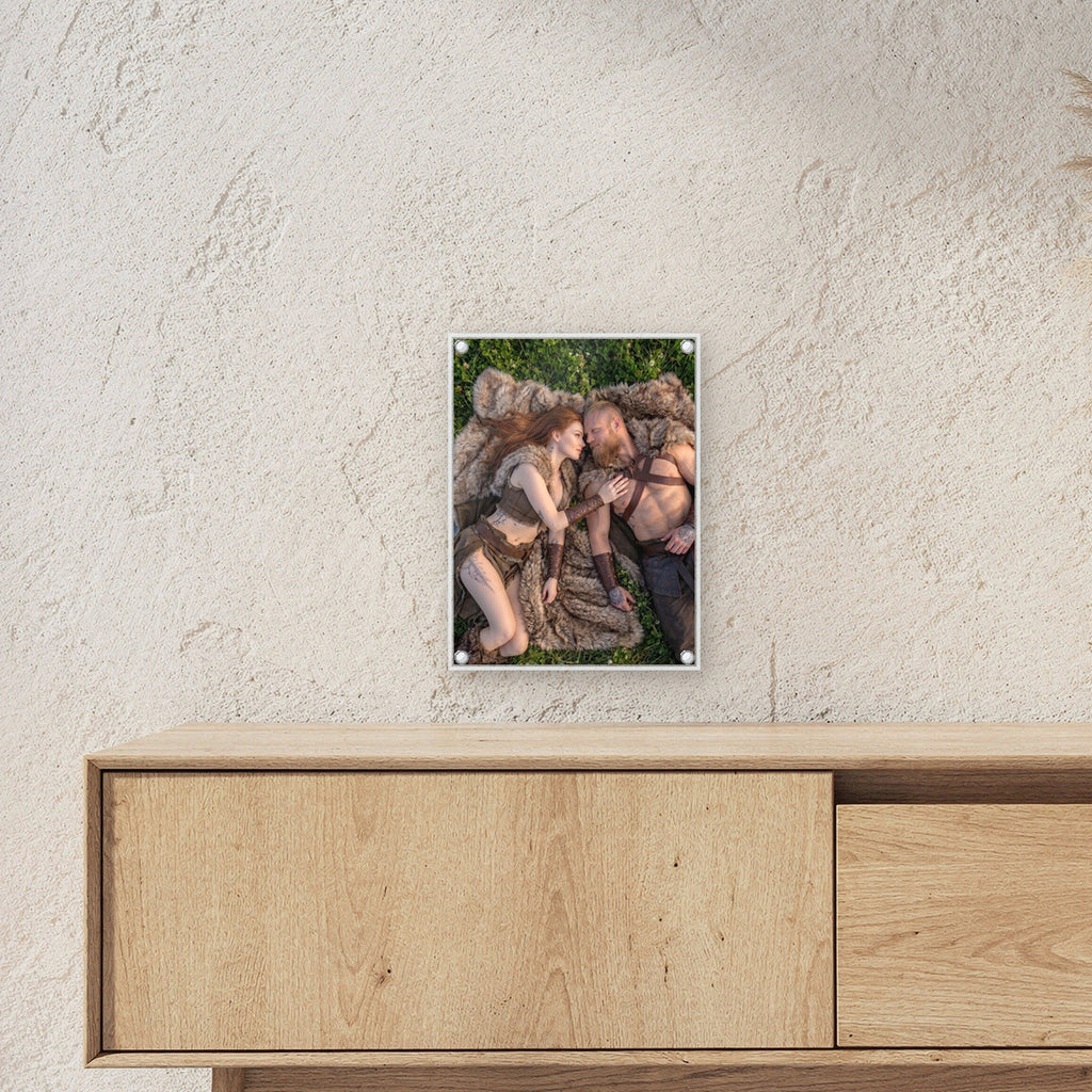 Nur wir zwei – Wikingerpaar liegt Kopf an Kopf auf einem Fell im Gras, auf Acrylglas mit Edelstahl-Abstandshaltern, über einem Sideboard, zeigt die Größe im Raum