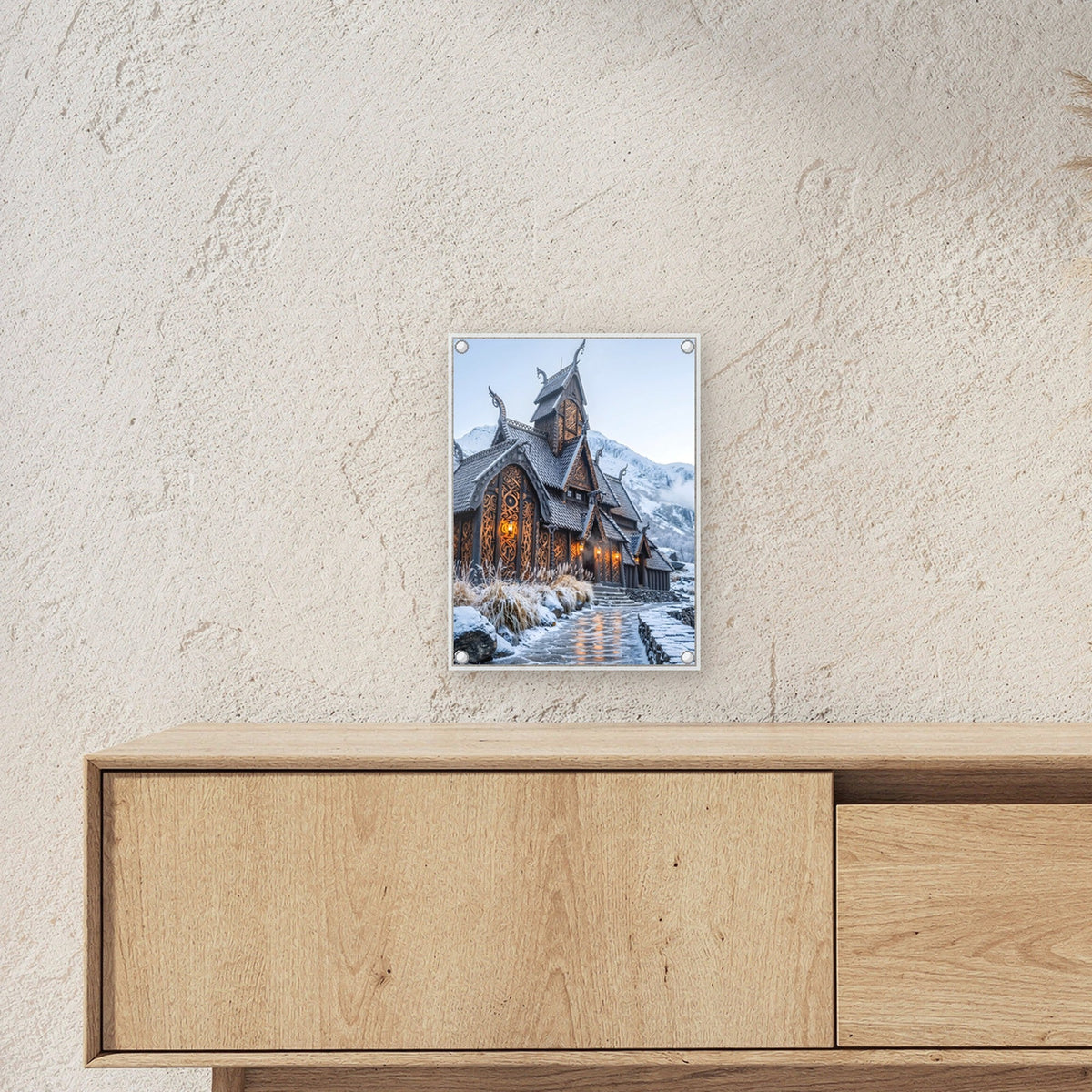 Stabkirche im Schnee – Nordische Stabkirche mit Drachenköpfen vor verschneiten Bergen, auf Acrylglas mit Edelstahl-Abstandshaltern, über einem Sideboard, zeigt die Größe im Raum