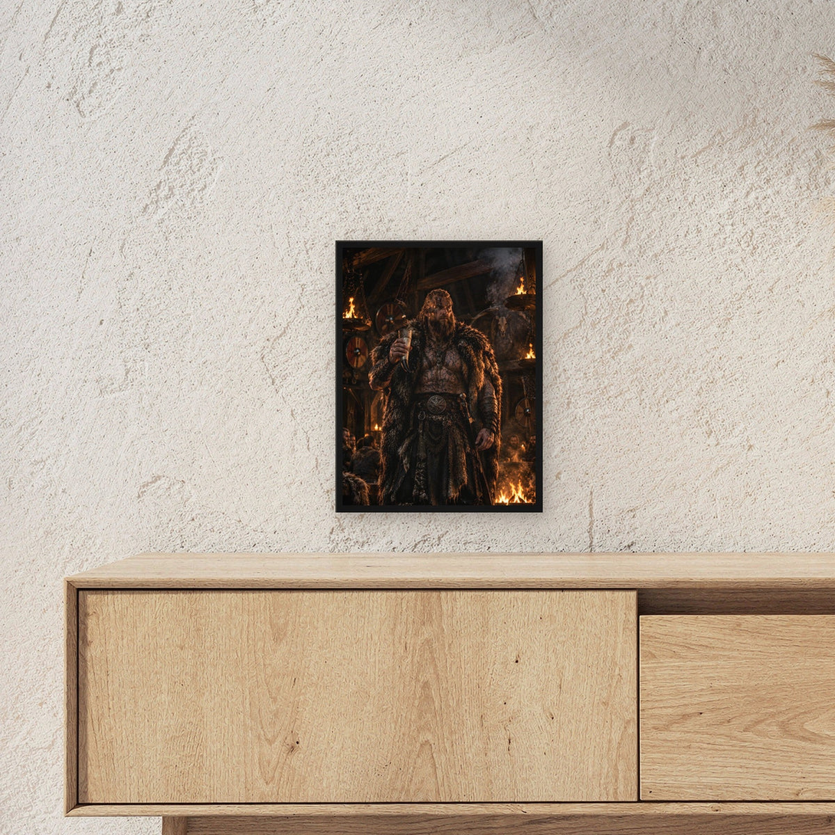Wikinger-Häuptling mit Trinkhorn in der Feuerhalle, Fantasy Wandbild gerahmt im schwarzen Holzrahmen ueber einem Sideboard, zeigt die Groesse im Raum